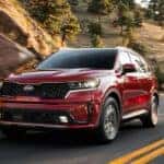 A used red 2021 Kia Sorento for sale driving on a highway.