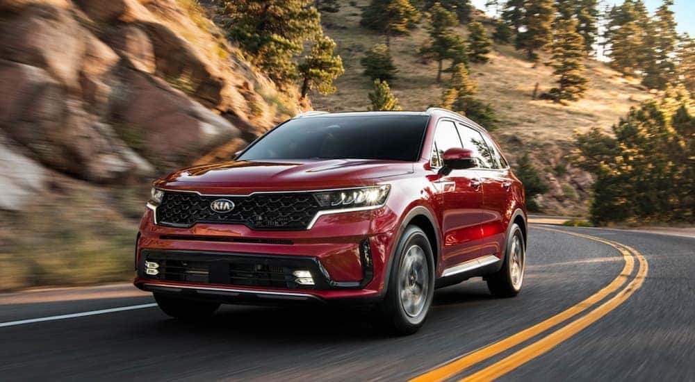 A used red 2021 Kia Sorento for sale driving on a highway.
