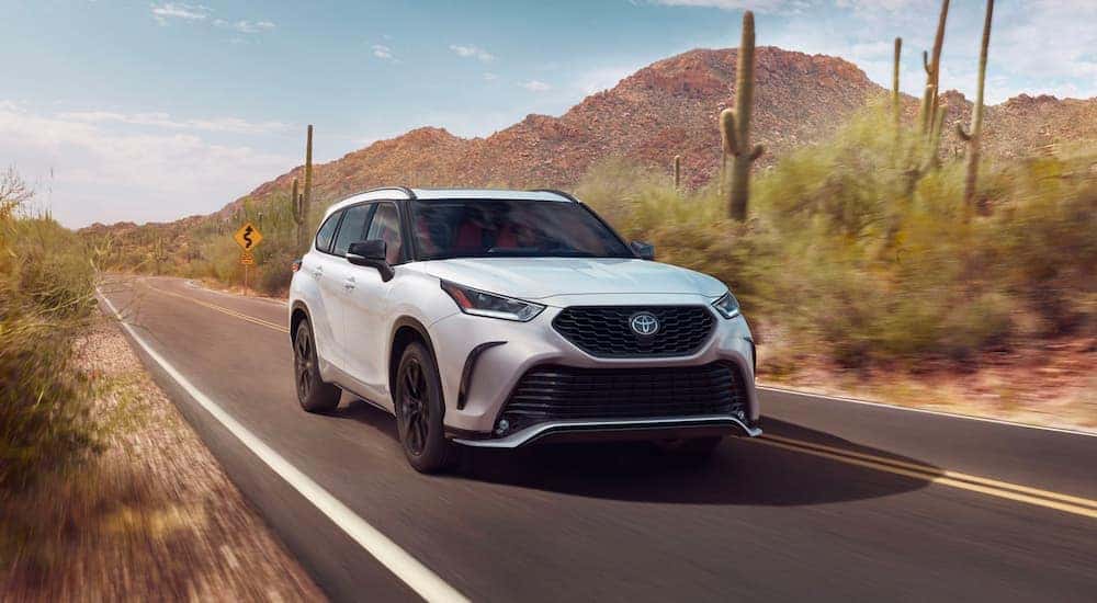 White 2023 Toyota Highlander XSE driving down an open road.