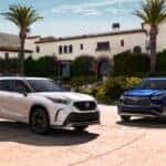 White and a blue 2023 Toyota Highlander parked beside each other outside a building.