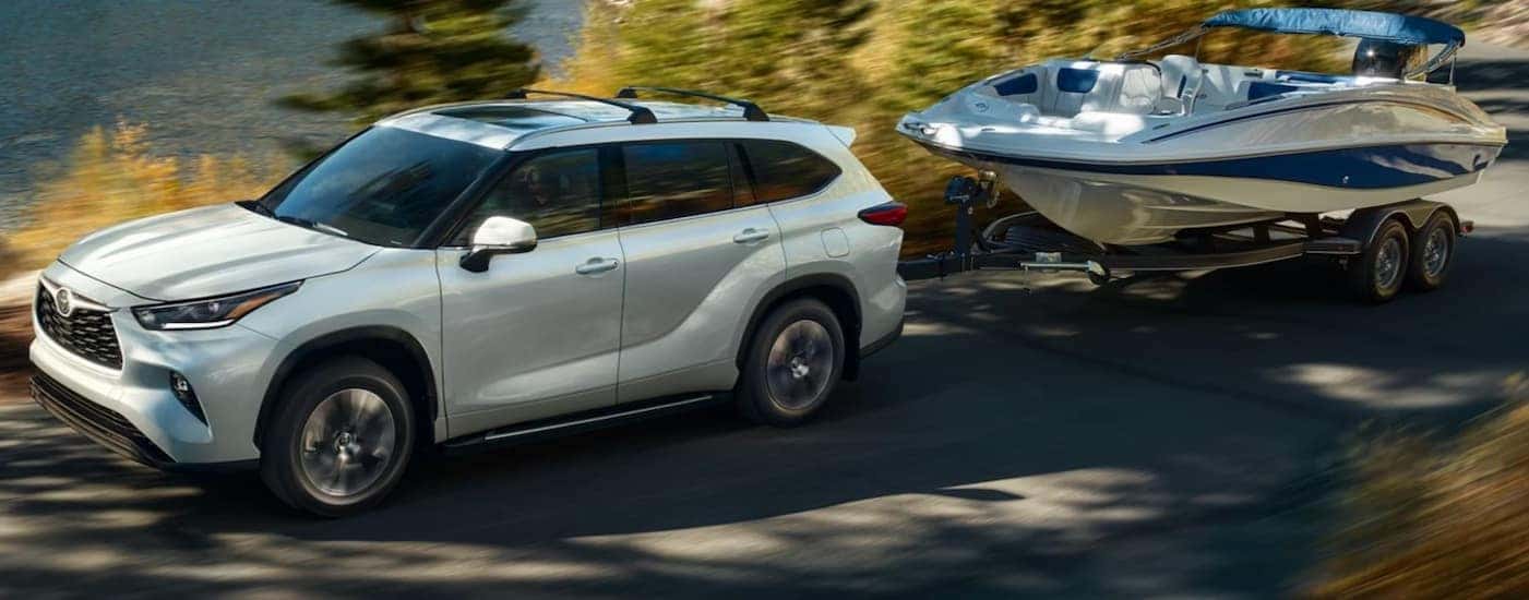A white 2025 Toyota Highlander towing a boat.