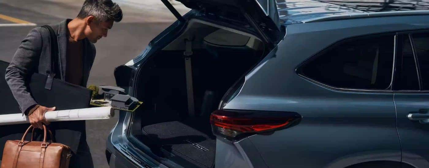 A person using the rear cargo in a blue 2023 Toyota Highlander Platinum.