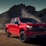 A red 2024 Chevy Silverado 1500 Trail Boss parked off-road.