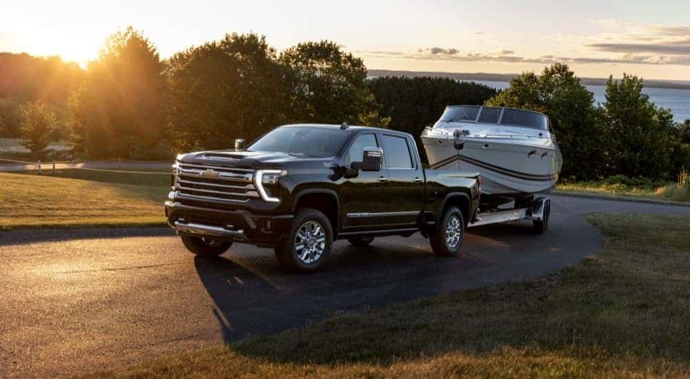 A black 2024 Chevy Silverado 2500 High Country towing a boat after viewing a Chevy Silverado for sale in Dallas.