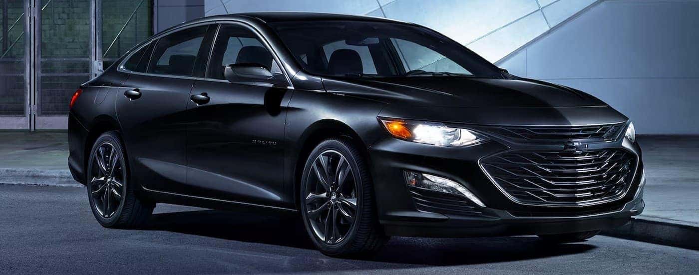 A black 2024 Chevy Malibu Midnight Edition parked in a city.
