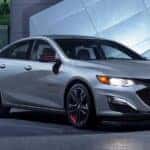 A silver 2024 Chevy Malibu 1LT parked in a city.