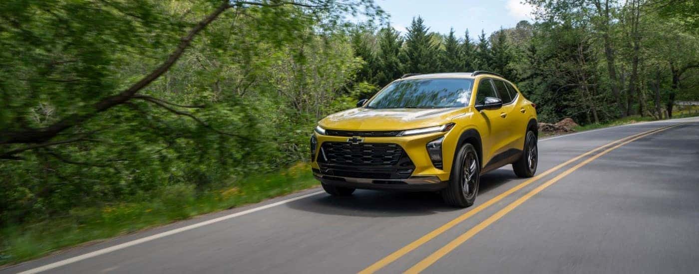 A yellow 2024 Chevy Trax ACTIV driving on a highway.