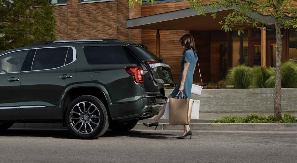 Woman putting bags in the back of a black 2023 GMC Acadia Denali