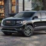 A black 2017 GMC Acadia parked near a house.
