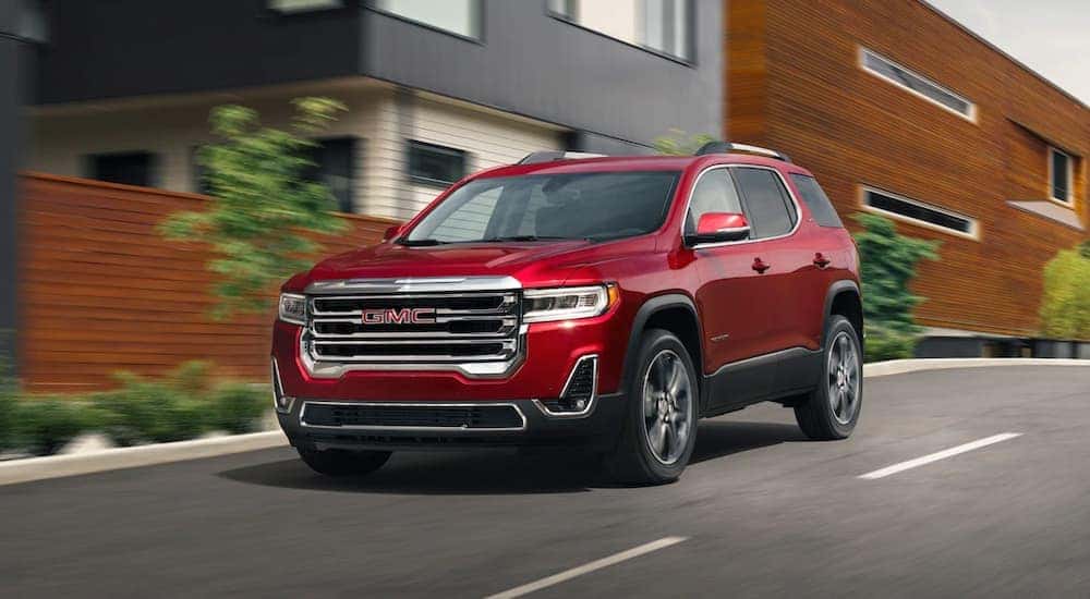 A red 2021 GMC Acadia for sale in Dallas driving on a city street.