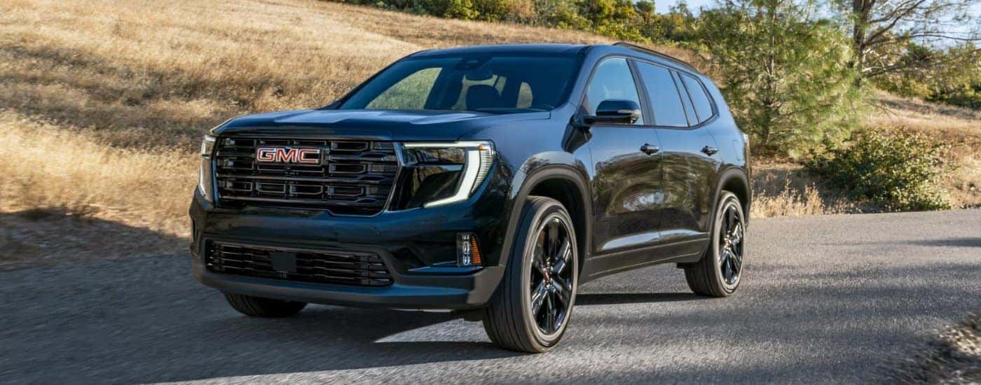 A black 2025 GMC Acadia Elevation parked off-road on gravel