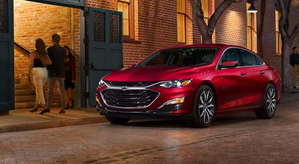 A red 2023 Chevy Malibu parked outside a home entrance