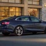 A dark blue 2023 Chevy Malibu parked outside a building