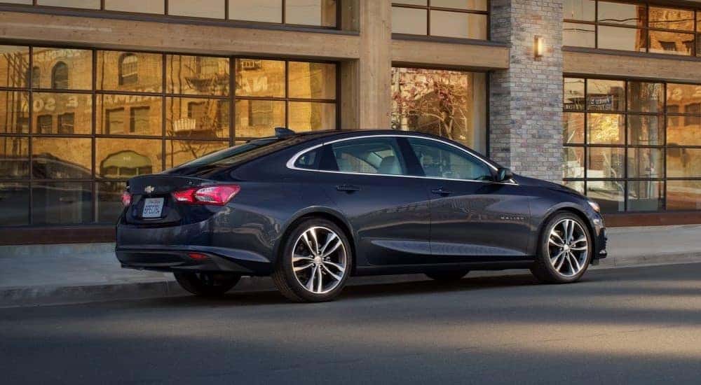 A dark blue 2023 Chevy Malibu parked outside a building