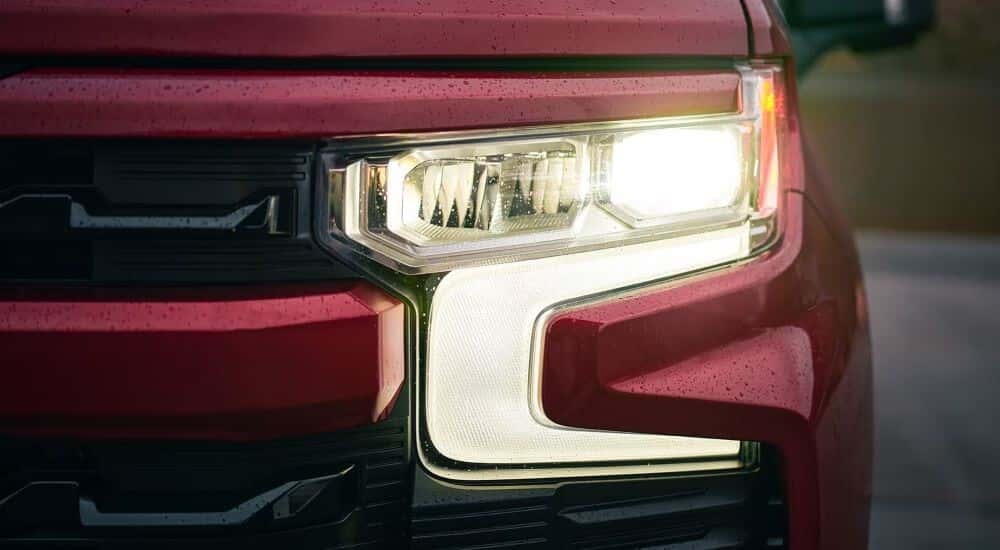 Close-up on the headlight of a red 2025 Chevy Silverado 1500.