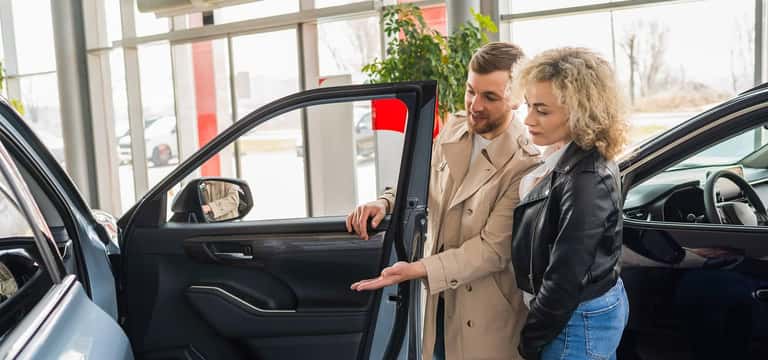 couple looking at car at dealership