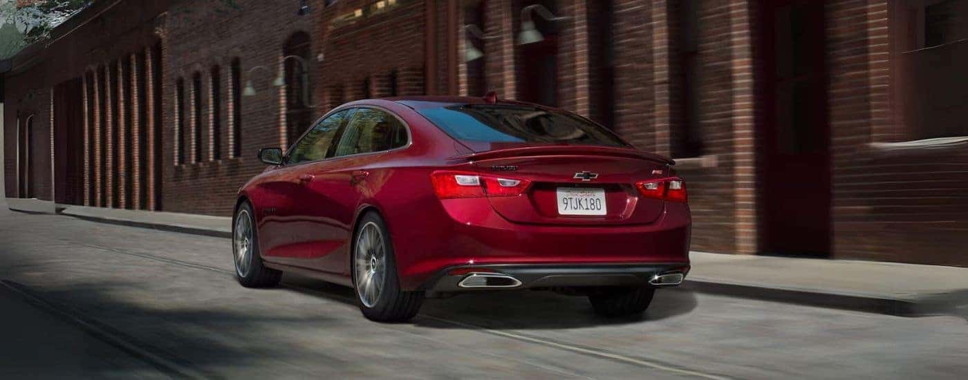 A red 2023 Chevy Malibu driving on a city street