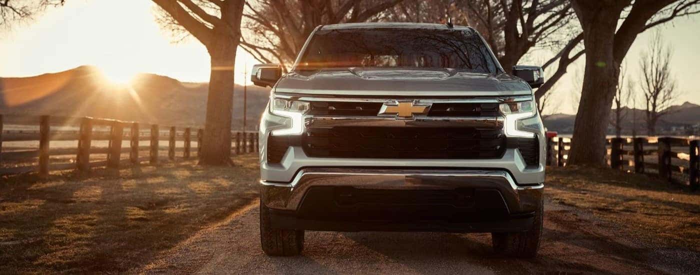 A silver used Chevy Silverado 1500 driving down a rural road