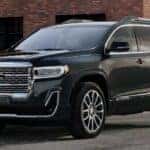 Black 2023 GMC Acadia for sale parked against a building at an angle.