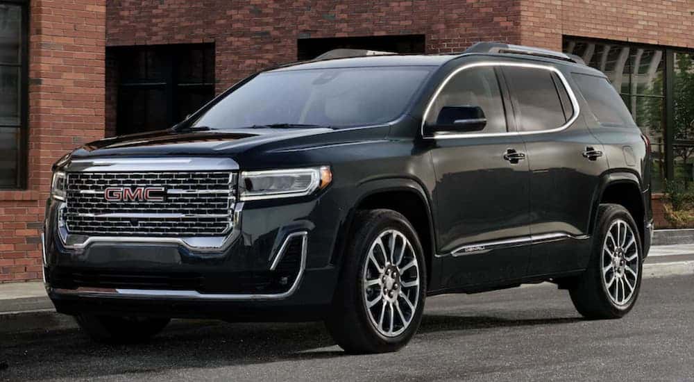 Black 2023 GMC Acadia for sale parked against a building at an angle.
