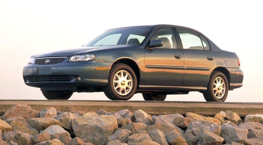 Blue 1997 Chevy Malibu from the side parked off-road.