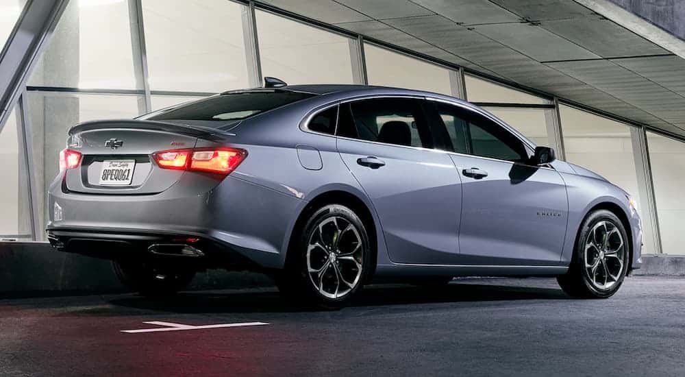 Silver 2019 Chevy Malibu driving down road from the side.