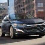 Blue 2022 Chevy Malibu from the front at an angle driving down the road.