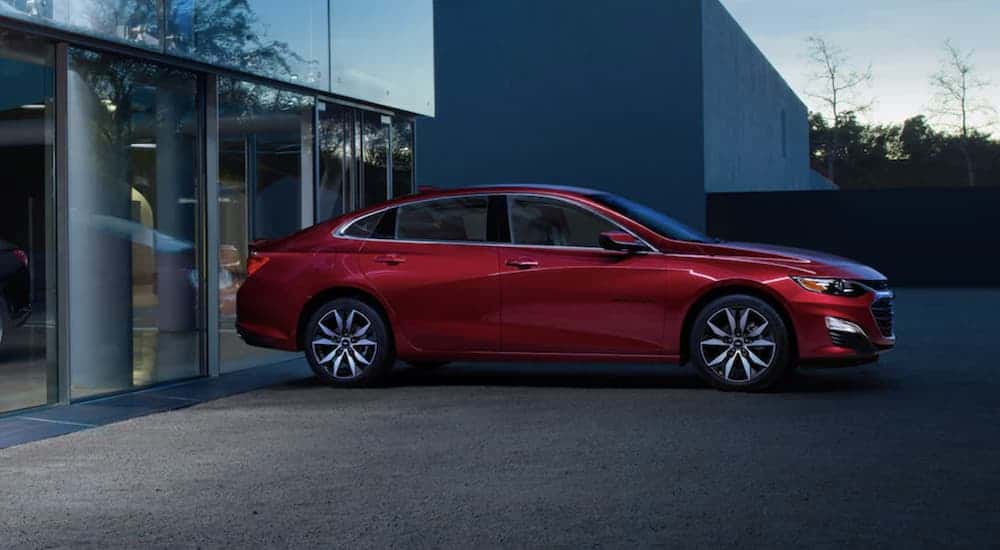 Red 2022 Chevy Malibu from the side parked in front of a building.