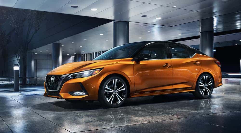 Orange 2021 Nissan Sentra for sale parked at an angle in front of a building.