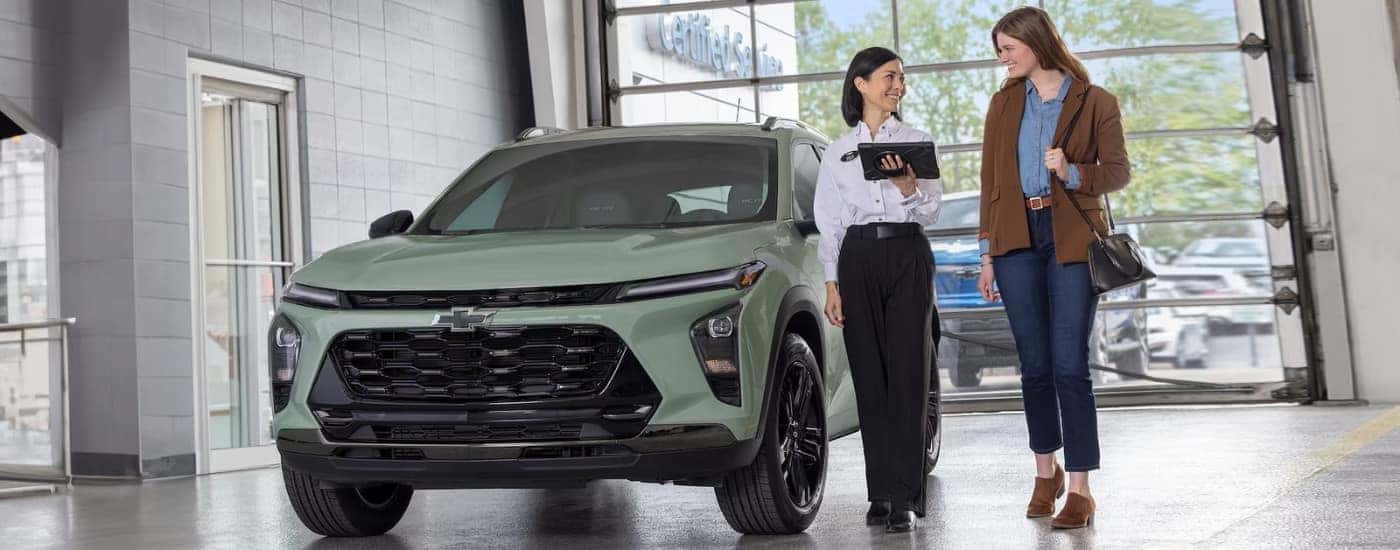 A salesperson and customer are shown walking past a 2024 Chevy Trax