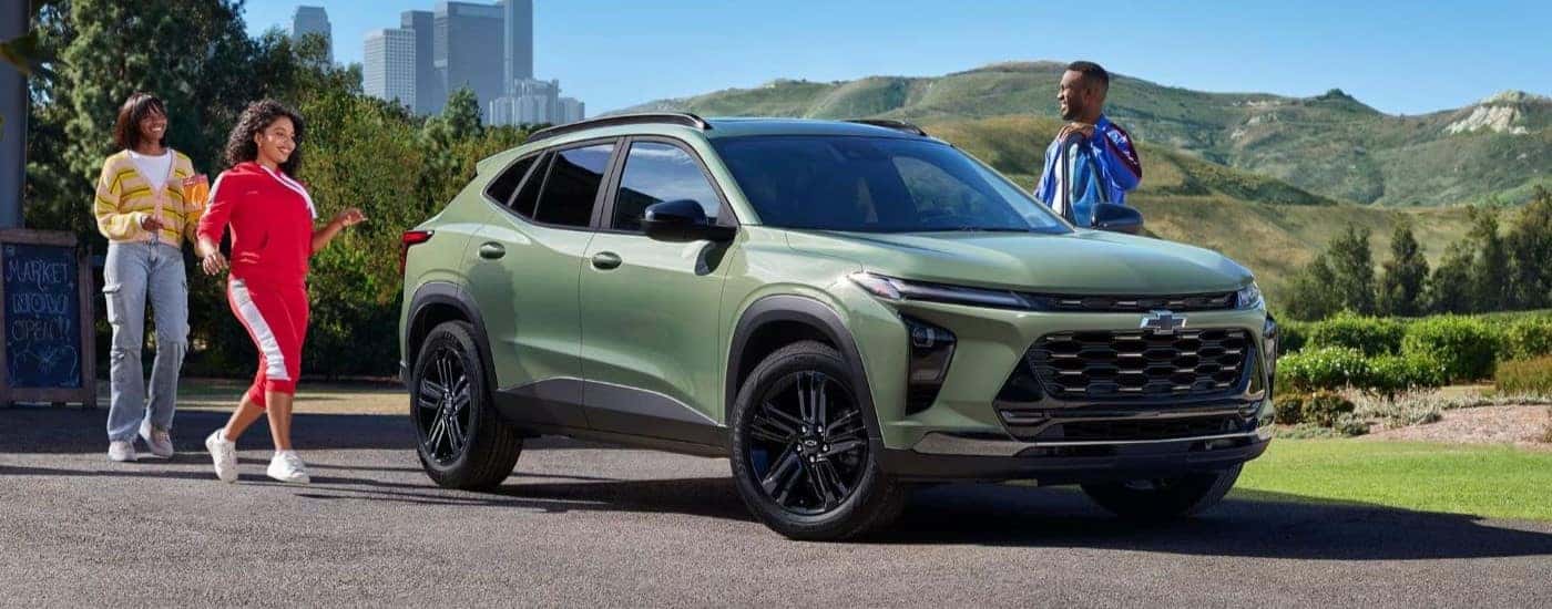 Three people walk up to a green 2024 Chevy Trax for sale in Fort Worth