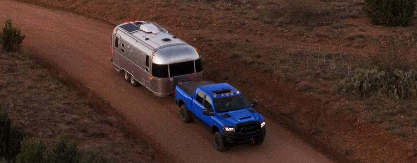 Blue 2024 Ram 2500 towing a camper that is for sale off-road