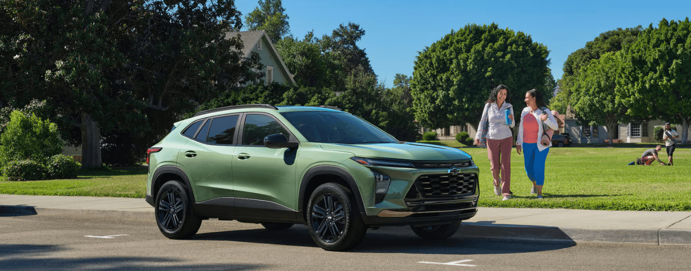Two people walk up to a green 2025 Chevy Trax for sale in Columbus
