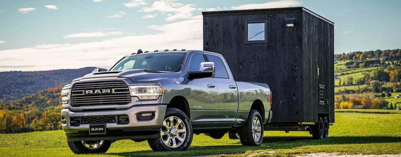 A silver 2023 Ram 2500 for sale towing a trailer.