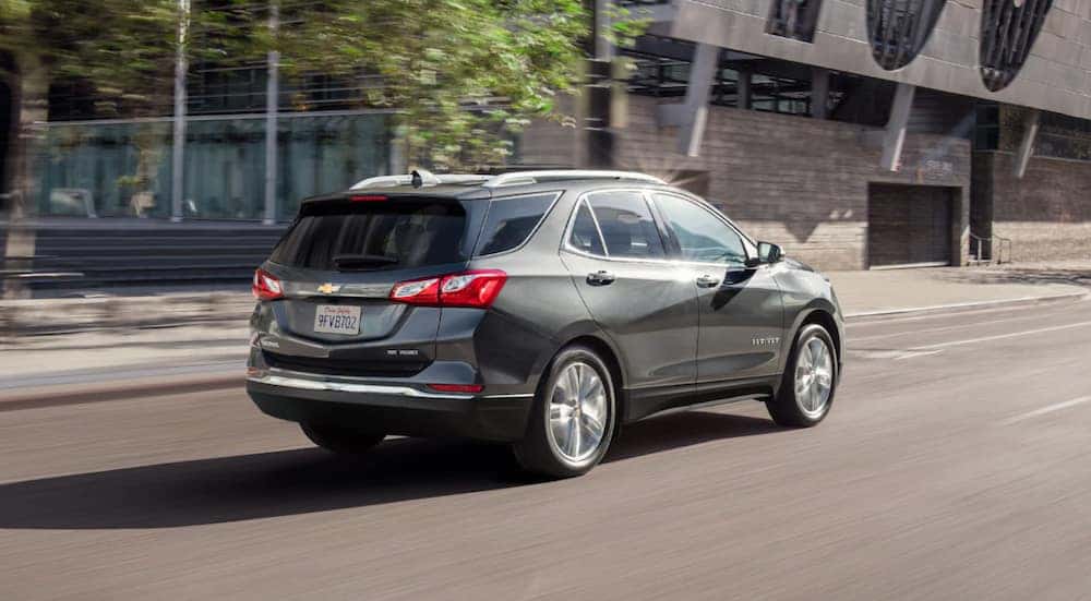 Rear of a grey 2021 Chevy Equinox driving down a city street.