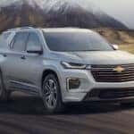 White 2022 Chevy Traverse driving down a road.