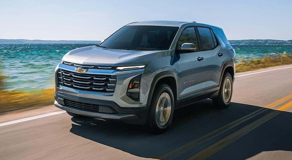 Silver 2025 Chevy Equinox driving down a road.