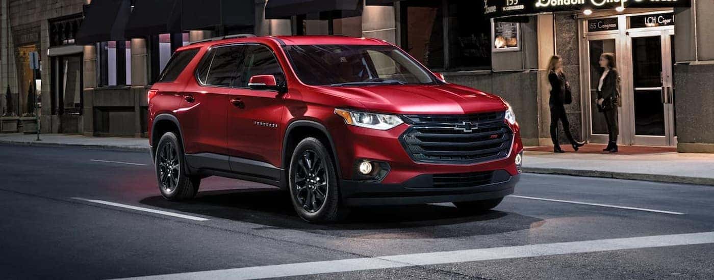 A red 2020 Chevy Traverse driving in a city at night
