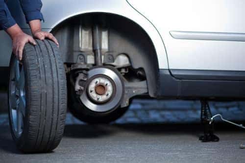 Man changes tire on car