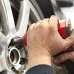 Close Up of hands of mechanic changing wheel of a limousine, with blurred background of garage.