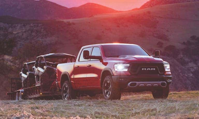 Red Ram 1500 towing boats over a hill at sunset