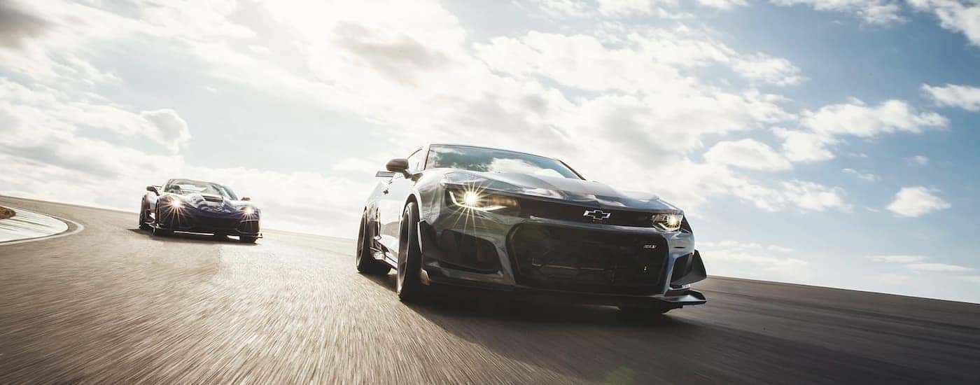 A black 2021 Chevy Corvette ZR1 and Camaro ZL1 are shown driving on a racetrack.