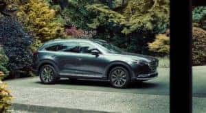 One of the most popular used cars near you, a grey 2021 Mazda CX-9, is shown parked on a driveway.