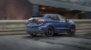A blue 2021 Ford Edge is shown driving in the rain.