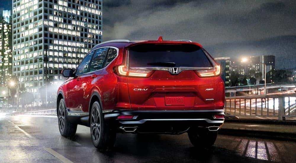 Red 2021 Honda CR-V Touring driving through a city at night.