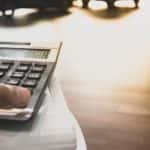 A person is shown using a calculator for auto financing Albany, NY.
