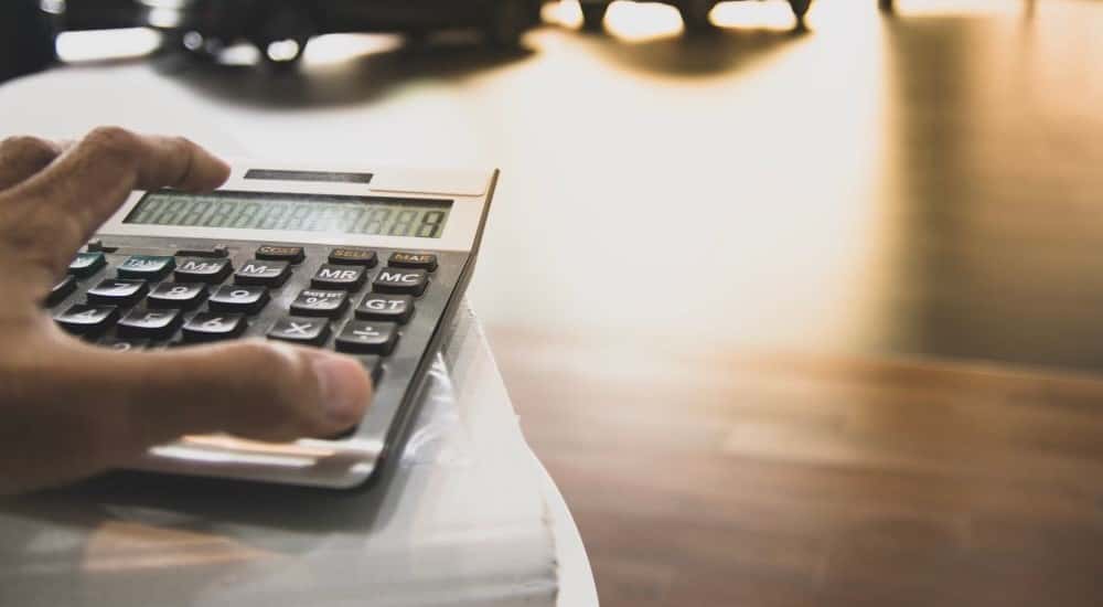 A person is shown using a calculator for auto financing in Albany, NY.