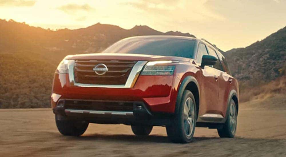 Red 2022 Nissan Pathfinder driving off-road in a desert.