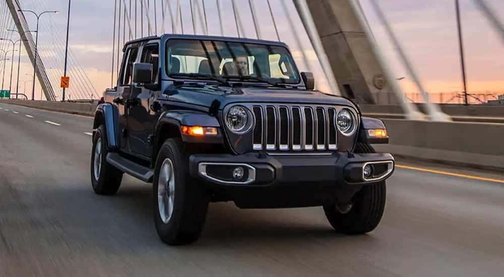 Grey 2022 Jeep Wrangler driving down a bridge.