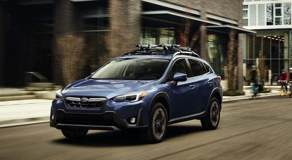 Blue 2023 Subaru Crosstrek driving in a city after leaving a used car dealership.